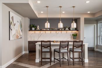 A kitchen with a marble countertop and wooden chairs.